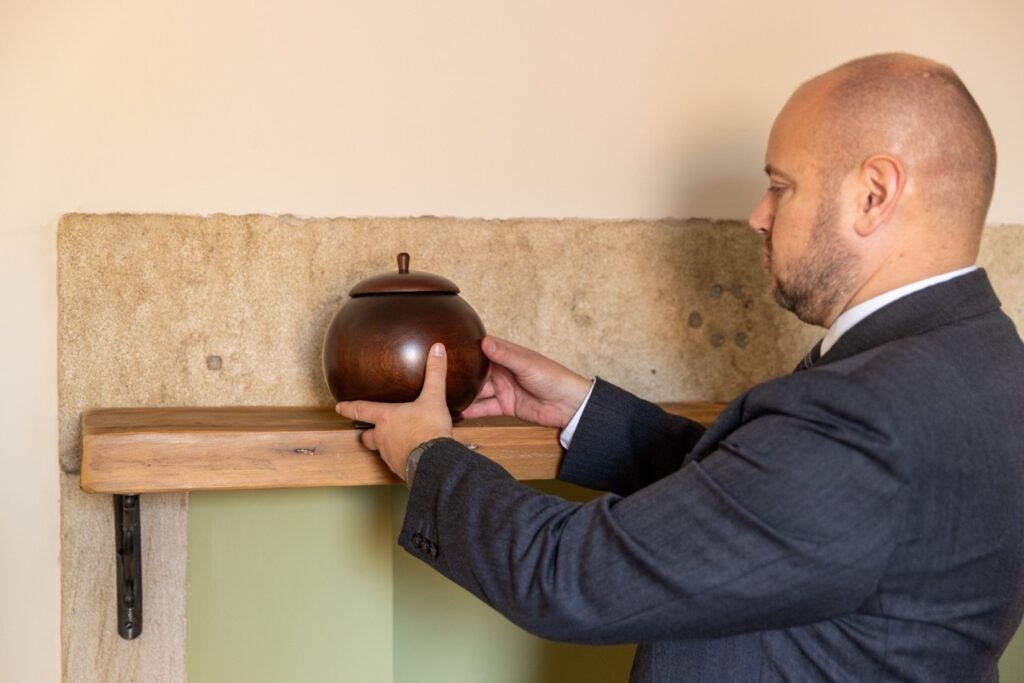 Photo of a funeral director carefully placing an urn on a shelf, preparing for the repatriation of ashes back home to loved ones