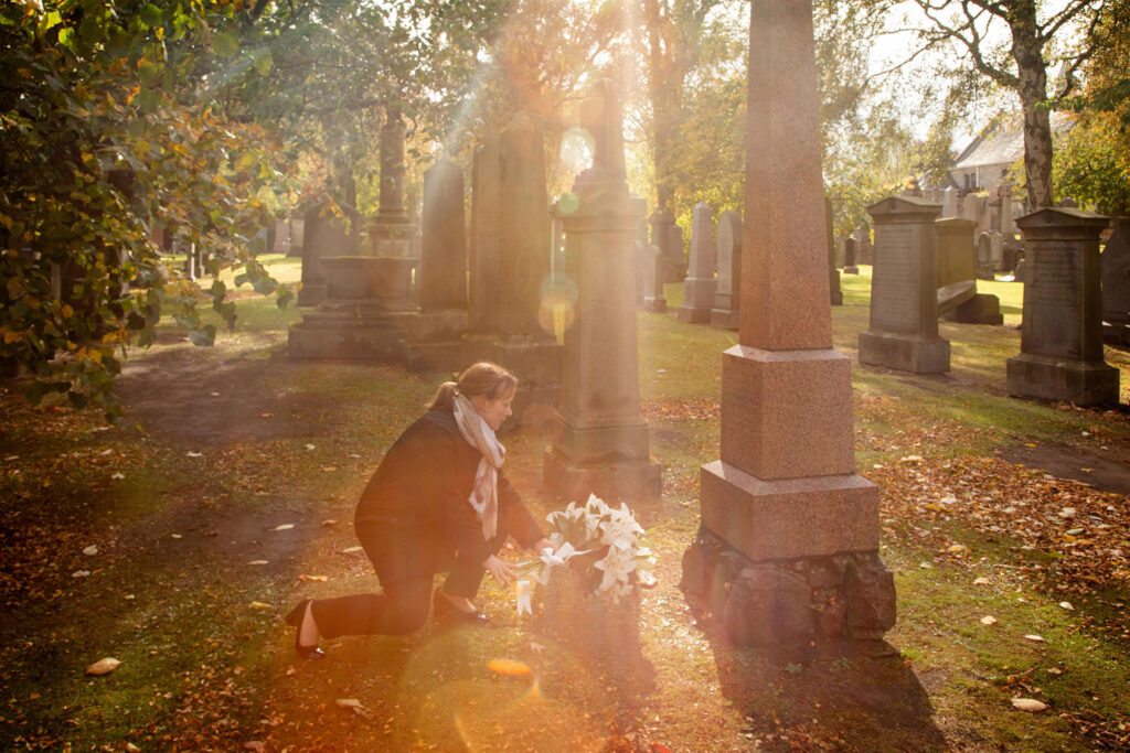 Photo of a woman laying flowers at a graveside