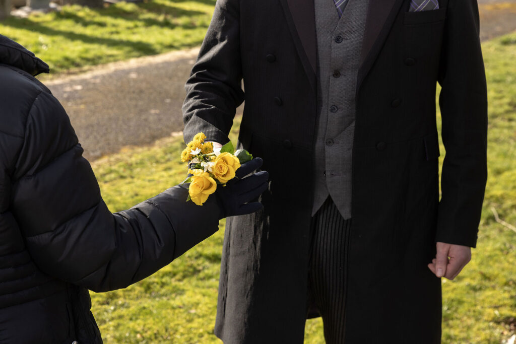 Photo of a funeral director handing a small bouquet of yellow flowers to a grieving relative